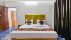 A neatly made bed with a colorful geometric-patterned bedspread, a wooden headboard, and two decorative pillows. - Fabhotel Nirvana Deluxe (Manali)