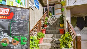 A staircase with potted plants, a chalkboard with restaurant options, and a sign indicating the establishment is open. - Fabhotel Nirvana Deluxe (Manali)