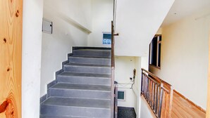 A staircase with wooden railings and a handrail, leading to an upper floor. - Fabhotel Nirvana Deluxe (Manali)