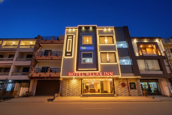 A multi-story hotel with a modern facade, a prominent 'HOTEL RELAX INN' sign, and a well-lit entrance.
