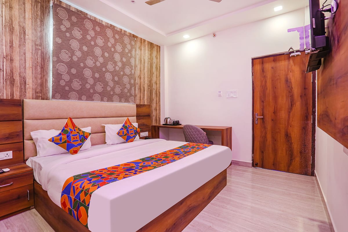 A bedroom with a large bed, wooden headboard, and a desk with a chair.