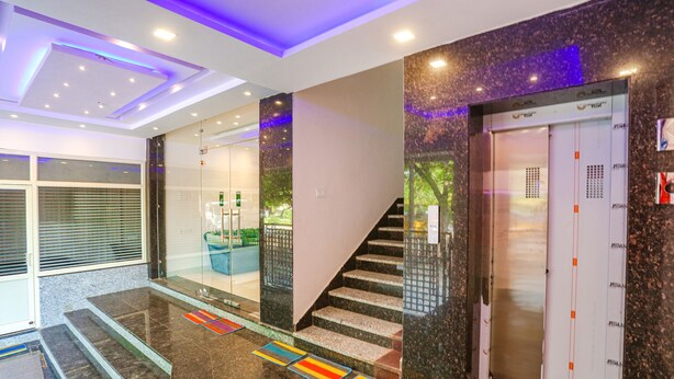 A modern lobby with a glass entrance, a staircase, and an elevator. - Fabhotel Relax Inn I (Kanpur)