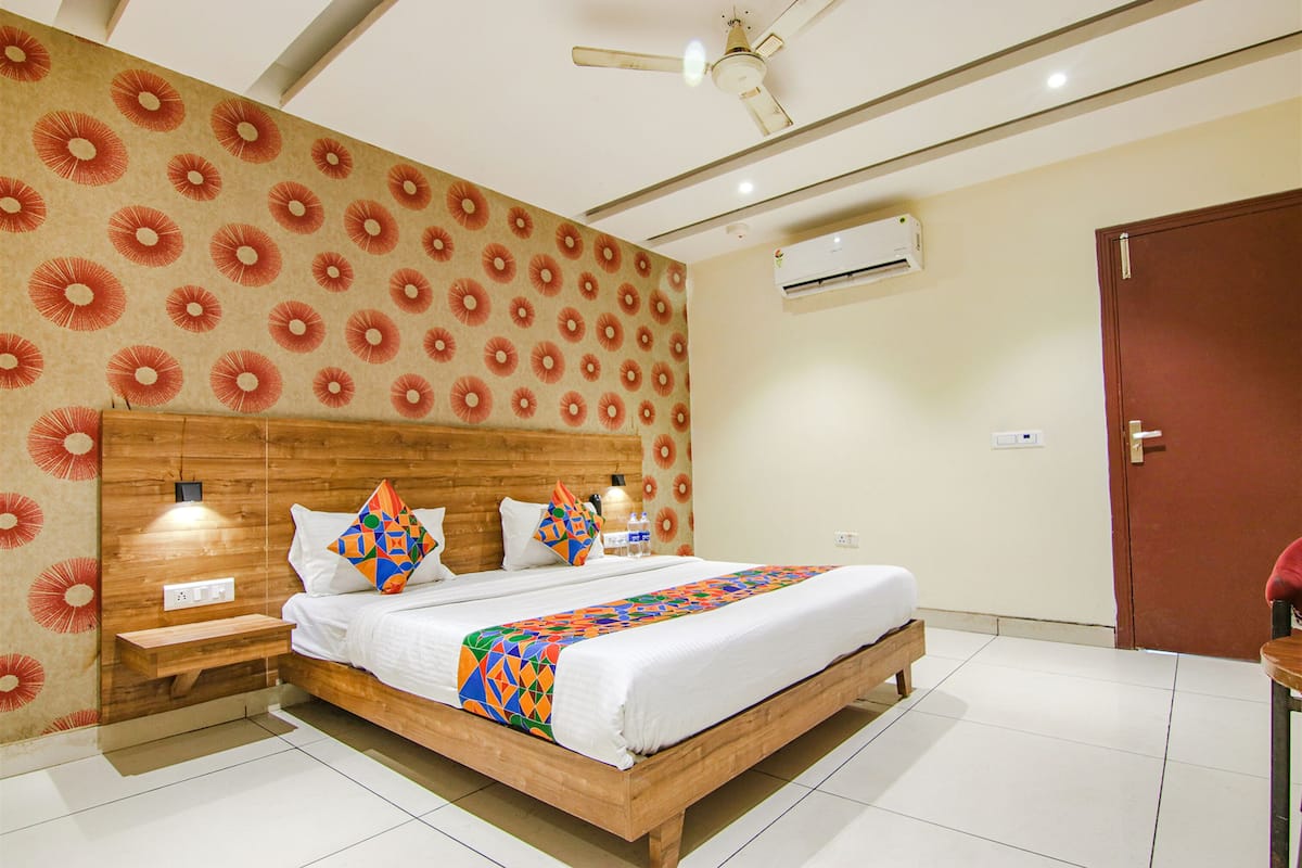 Una habitación de hotel moderna con una cama de madera, un papel tapiz estampado y un ventilador de techo.