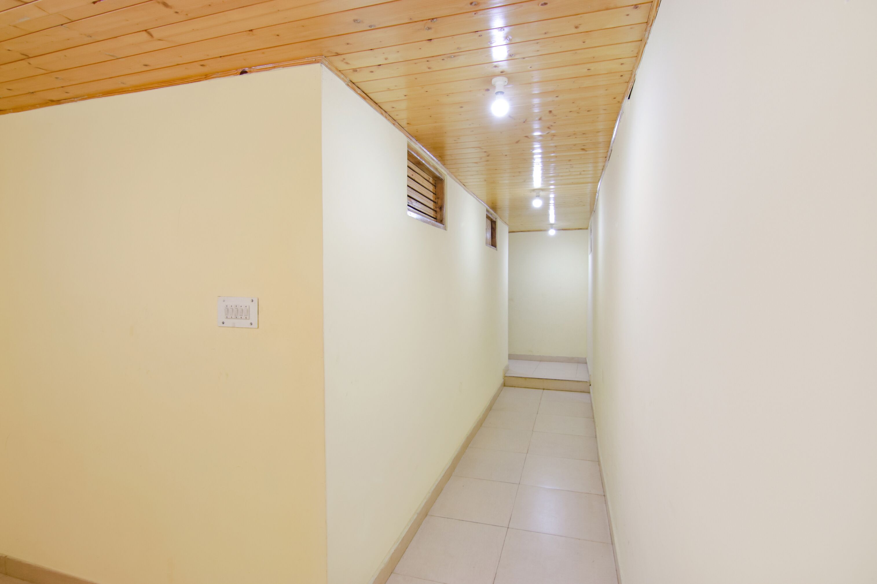 A narrow hallway with wooden ceiling and light-colored walls.