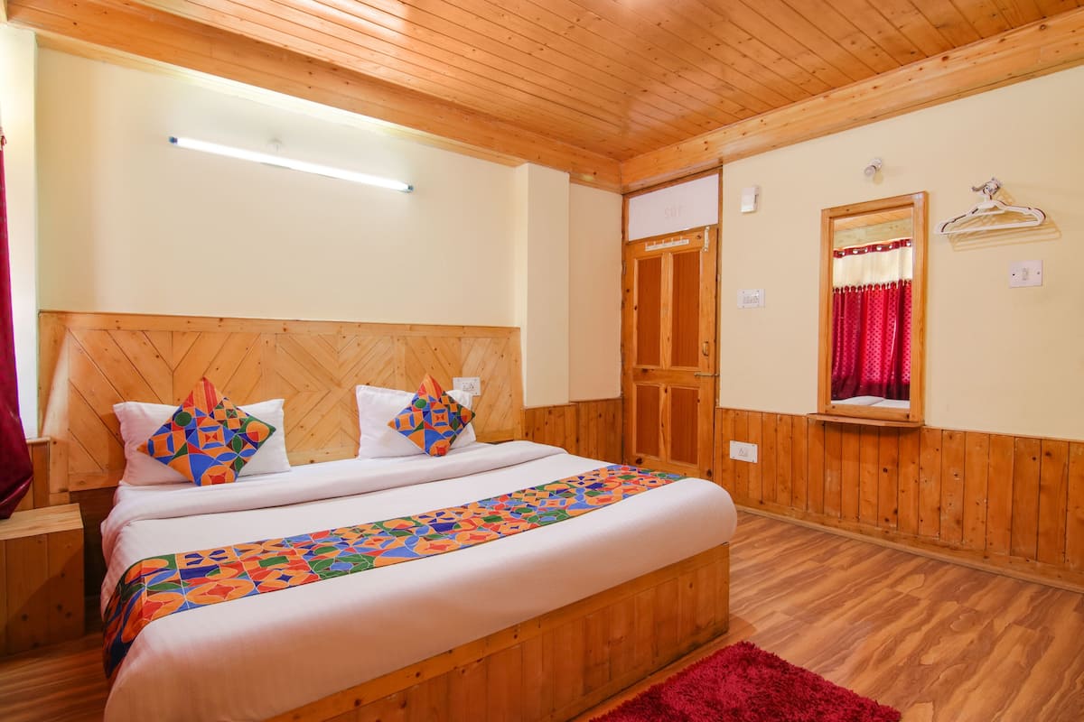 A wooden-paneled bedroom with a bed, a red rug, and a mirror with a red curtain.