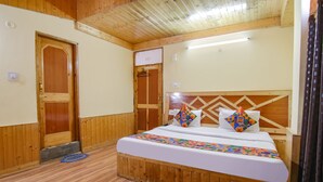 A wooden-paneled bedroom with a bed, a door, and a wall-mounted light fixture. - Fabhotel Orchard Retreat (Manali)