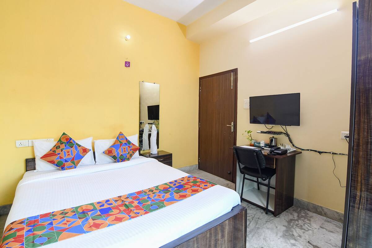 A hotel room with a bed, a desk, a chair, a TV, and a wardrobe.