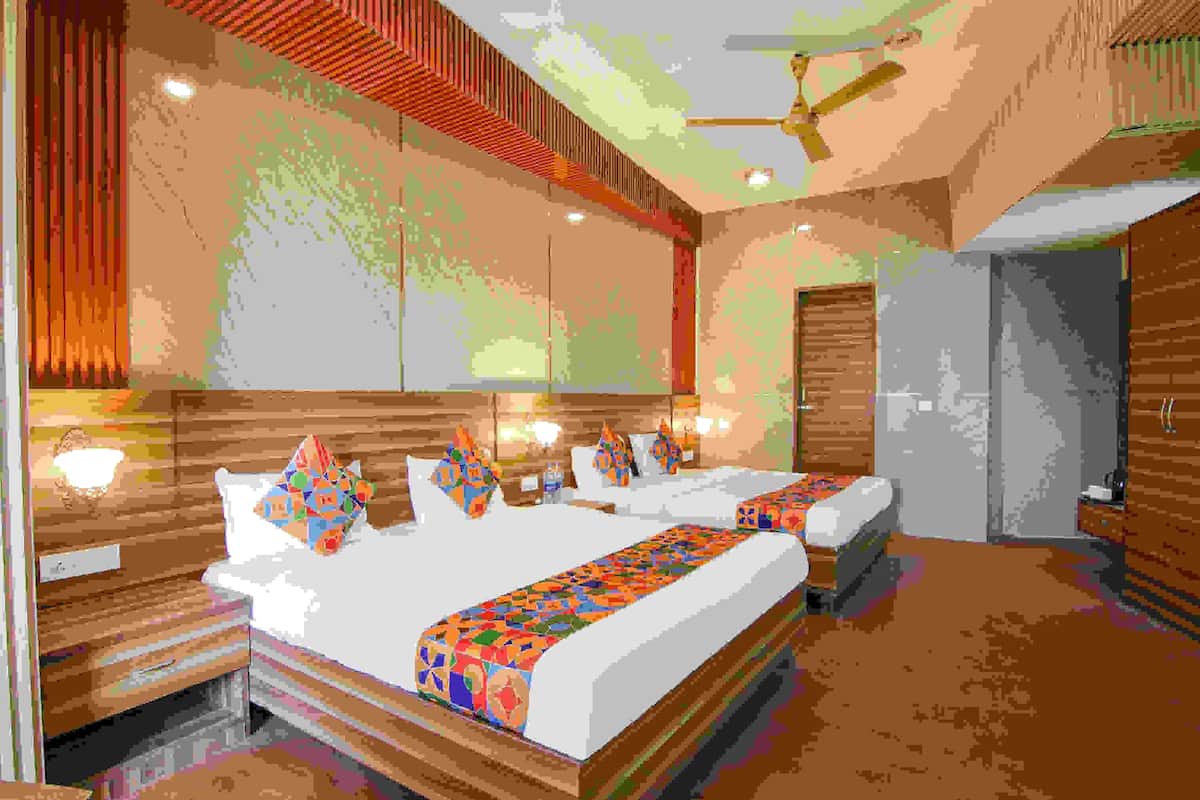 A hotel room with a large bed, a desk, and a wardrobe.