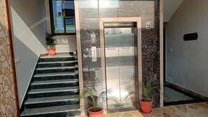 Una scala che conduce a un ascensore, con piante in vaso alla base.
