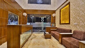 Una hall d'albergo moderna con una scrivania di ricevimento in legno, un divano e una moquette a motivi.