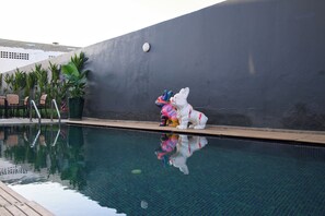 Une piscine avec un poste de surveillance pour sauveteur et une statue d’ours.