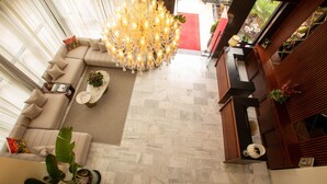 Una sala de estar moderna con una lámpara de araña grande, un sofá color beige, una mesa de centro y una planta en maceta.