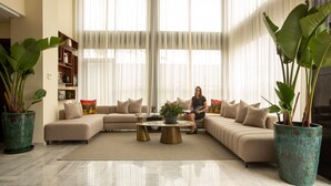 Una sala de estar con un sofá modular, una mesa de centro y plantas grandes en macetas.