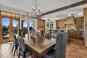 A spacious kitchen with wooden cabinets, a large dining table, and a chandelier.