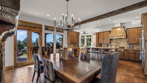 A spacious kitchen with wooden cabinets, a large dining table, and a chandelier.