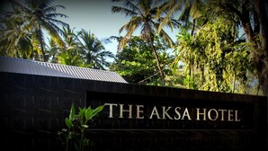 A sign for The Aksa Hotel with a dark background and gold lettering. - The Aksa Hotel (Mumbai)