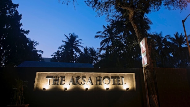 The exterior of The Akasa Hotel with a prominent sign and a tree in the foreground. - The Aksa Hotel (Mumbai)