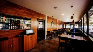 A restaurant with wooden walls, a bar area, and tables and chairs arranged for dining. - The Aksa Hotel (Mumbai)