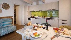 A modern kitchen with white cabinets, a green backsplash, and a dining area with a table set for a meal. - The Chic Lino Delle Fate Eco Resort Num4054 (San Michele al Tagliamento)