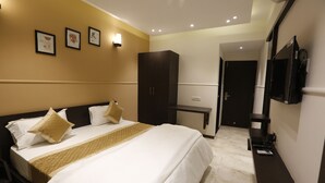 A hotel room with a bed, a wardrobe, a desk, and a TV. - Hotel Maple Inn (Ahmedabad)