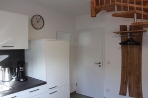 A kitchen with white cabinets, a black countertop, a coffee maker, and a wooden staircase. - Ferienwohnung Brack in Gaggenau, Schwarzwald (Gaggenau)