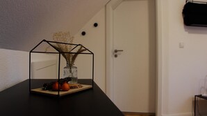 Et værelse med et sort bord, en glaskrukke med tørrede planter og en dør i baggrunden.