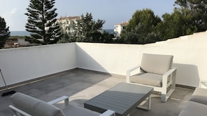 Terraza en la azotea con dos sofás blancos, una mesita y una escoba.