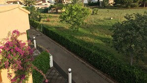 Una calle residencial con casas, un área verde y cielo despejado.