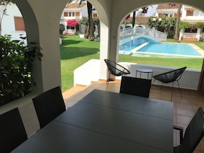 En terrasse med et bord og stole, en pool og et hvidt hegn.
