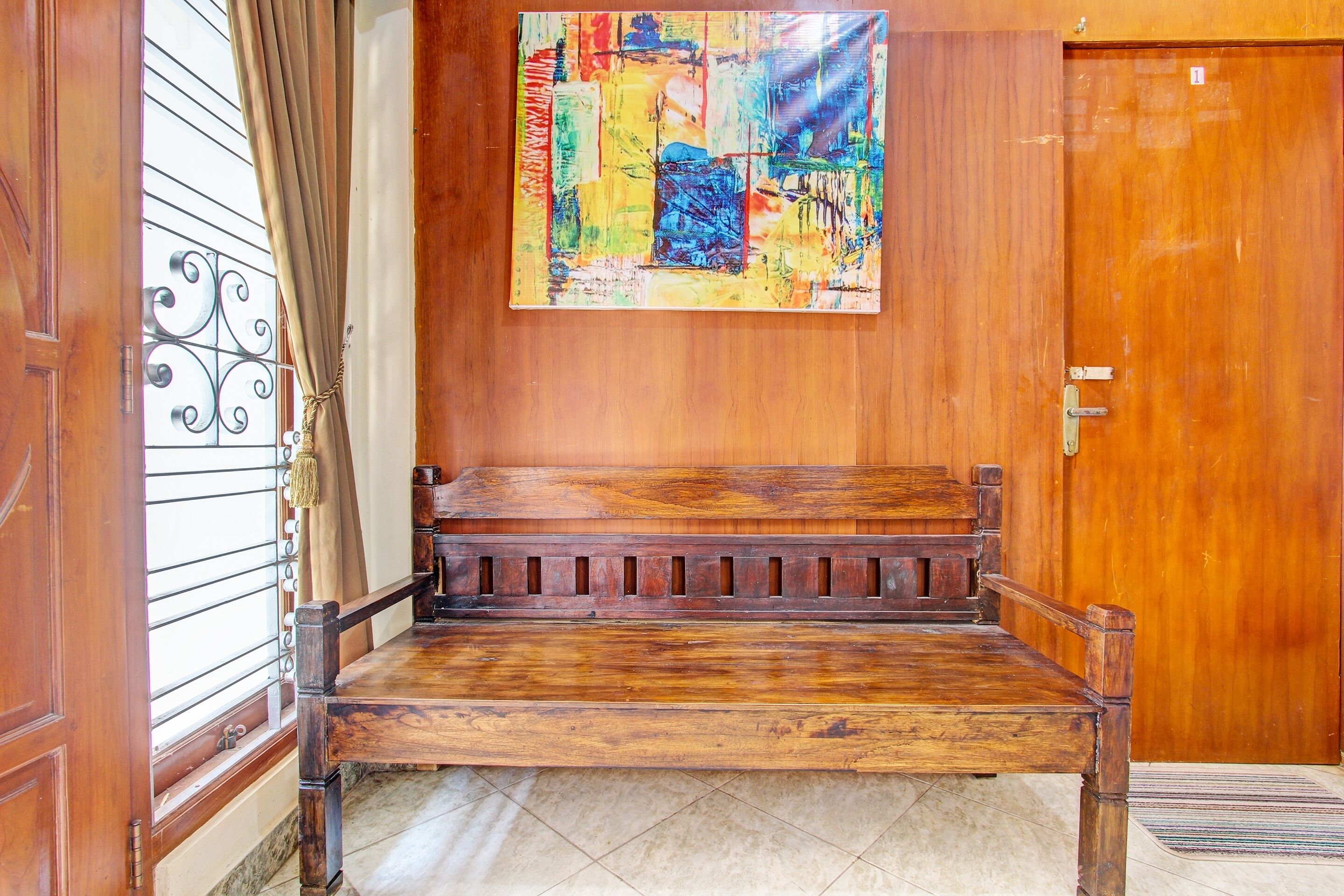 A wooden bench in a room with a wooden door and a window with metal bars.