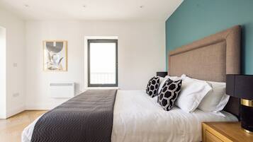 A bedroom with a bed, bedside tables, a window, and a wall-mounted artwork.