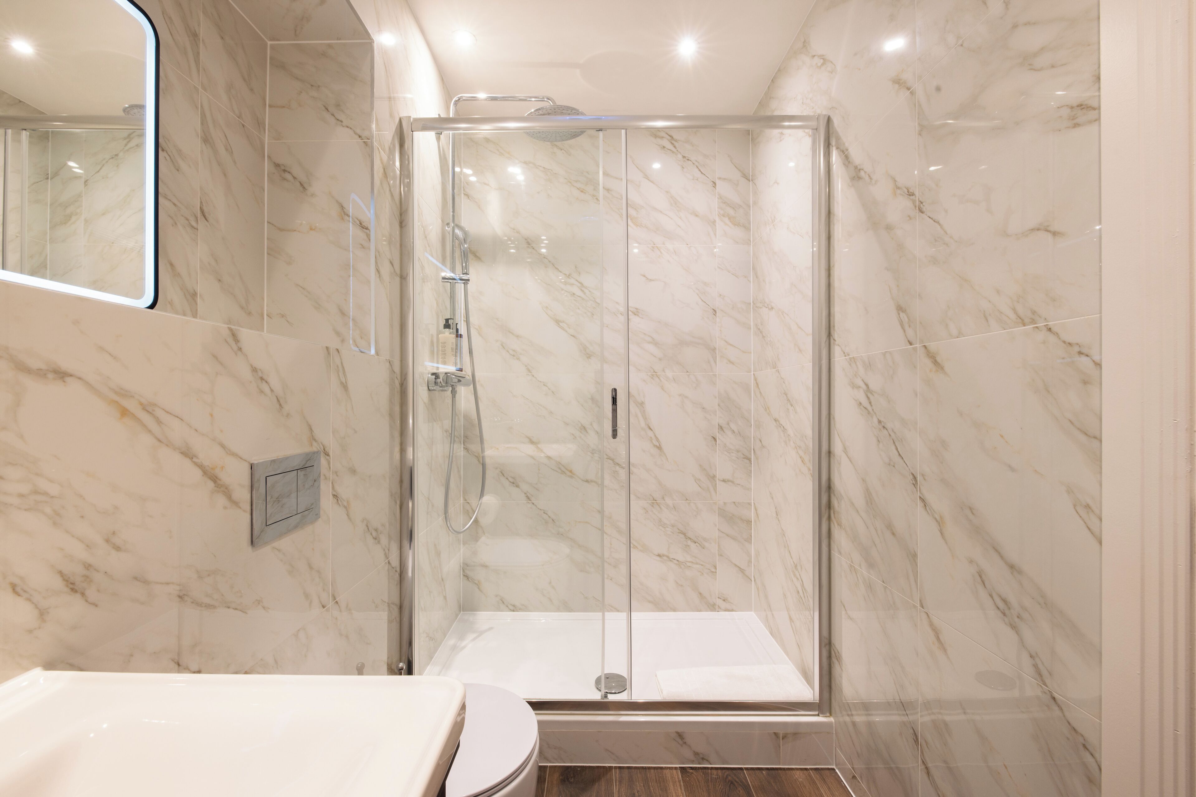 A modern bathroom with a glass-enclosed shower, a toilet, and a sink.