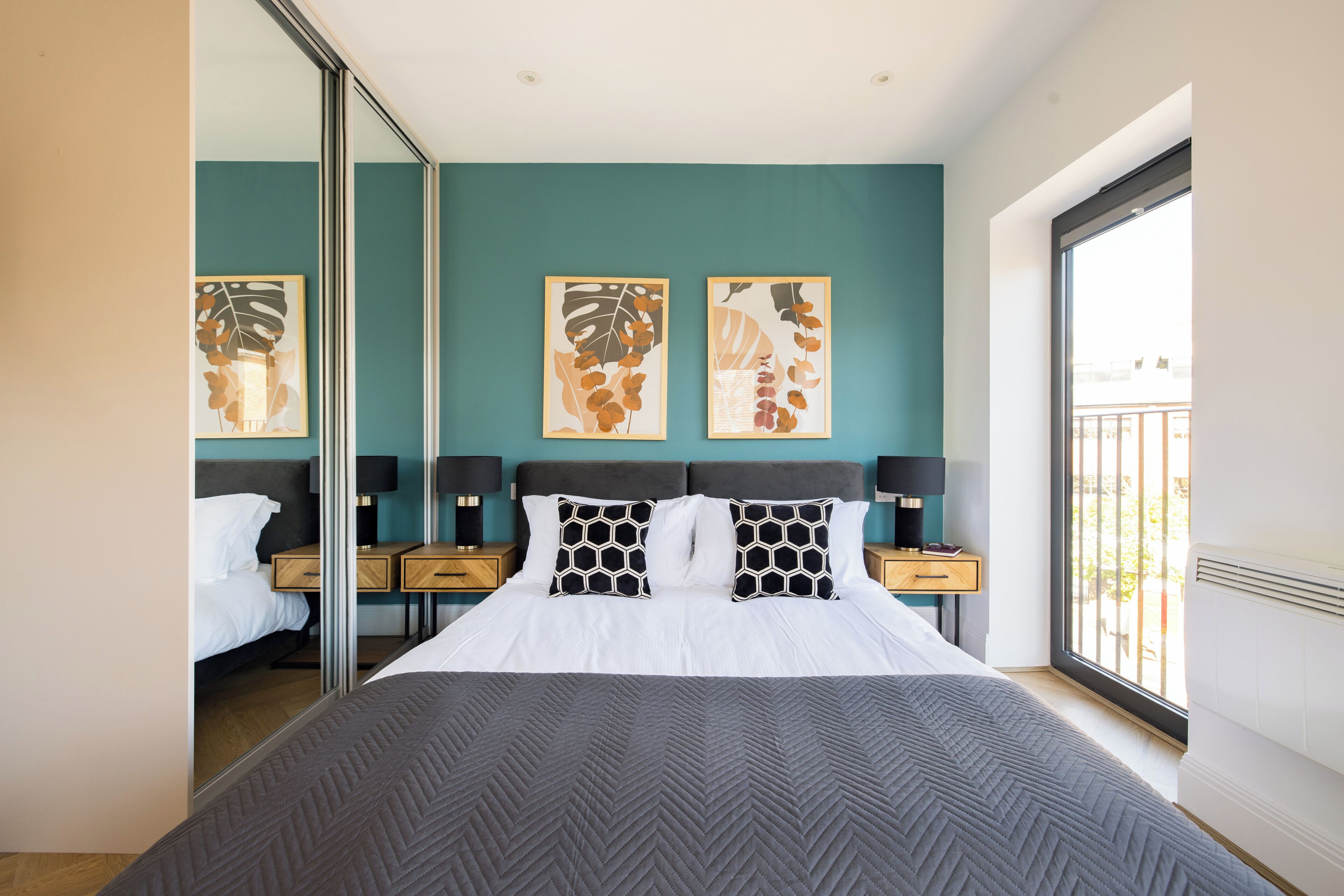 Una habitación de hotel moderna con una cama grande, vistas de la ciudad y obras de arte en la pared.