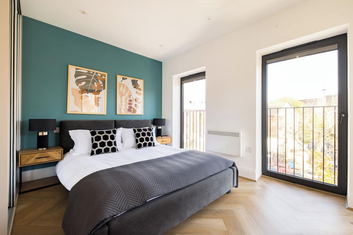 A bedroom with a bed, nightstands, a window, and artwork on the wall.
