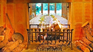 Une cheminée avec des bûches et un foyer, entourée de rondins de bois.