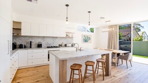 Een moderne keuken met witte kasten, een marmeren aanrecht en houten krukken.