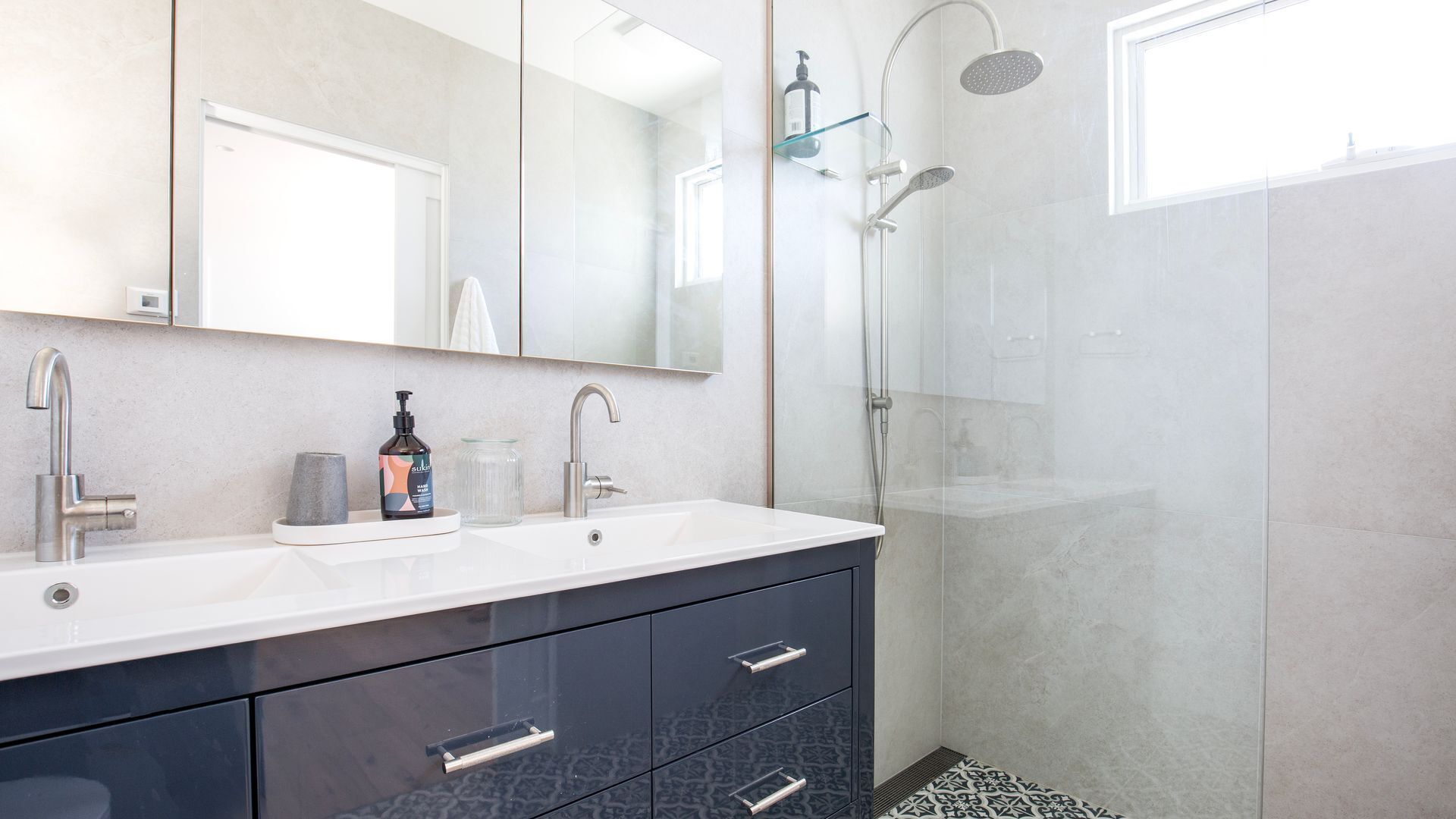 Une salle de bain moderne avec un meuble-lavabo à deux vasques, une douche à parois de verre et un grand miroir.