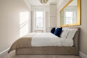 Een slaapkamer met een bed, een grote spiegel en een raam.