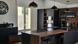 Una cocina moderna con una isla central, iluminación colgante y horno empotrado.