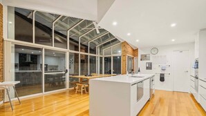 A modern kitchen with a large island, glass sliding doors leading to a dining area, and a visible kitchen counter.