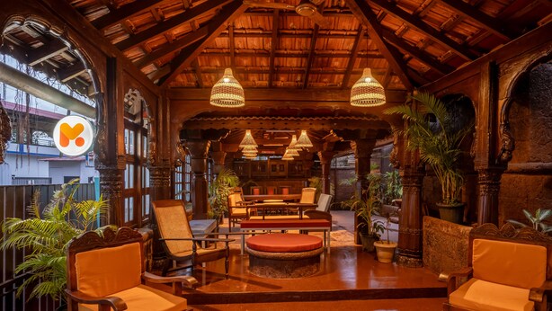 A cozy, rustic interior with wooden furniture, a thatched roof, and hanging lamps.