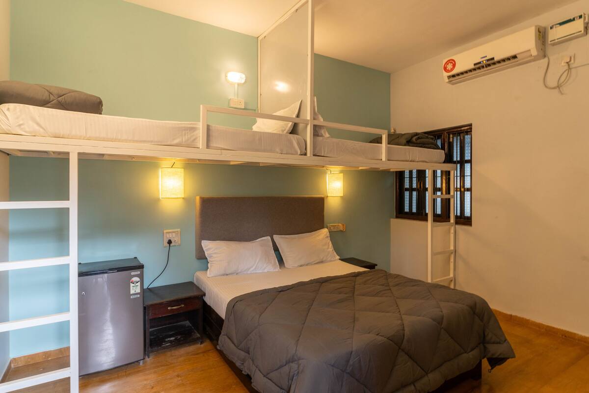 Habitación con literas, un escritorio, un refrigerador pequeño y una ventana con persianas.