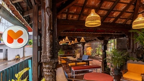 A covered outdoor seating area with wooden furniture and hanging lamps.