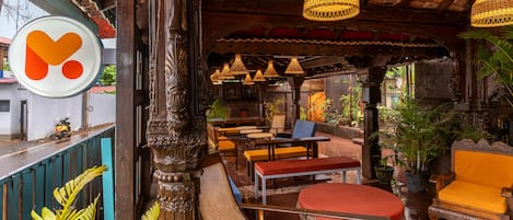 A covered outdoor seating area with wooden furniture and hanging lamps.