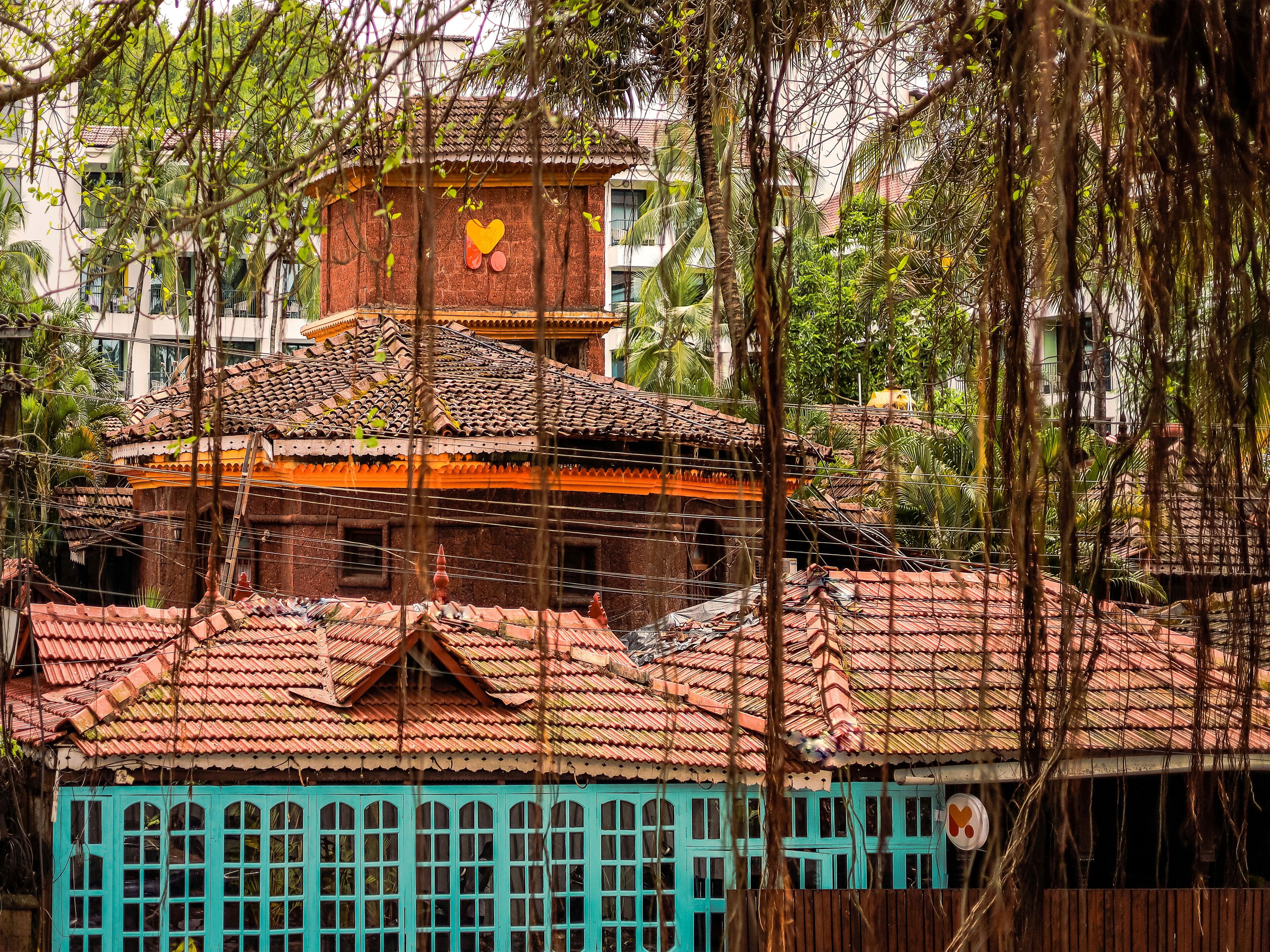 A traditional building with a tiled roof, a small tower with a heart-shaped window, and a turquoise facade.