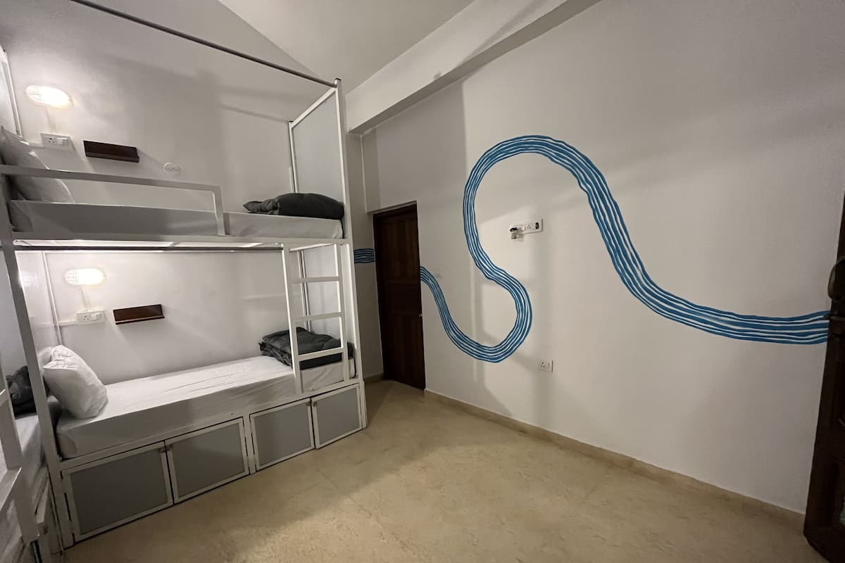 Habitación tipo dormitorio con literas, un escritorio y una pared con un diseño abstracto azul.