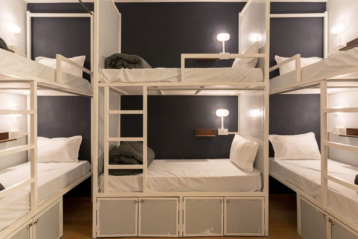 Habitación con literas blancas, una escalera y lámparas de noche.