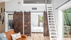 A loft-style bedroom with a loft bed, a wooden ladder, and a sliding barn door. - Romantic Beehive Treehouse Getaway in Nature (Pittsboro)