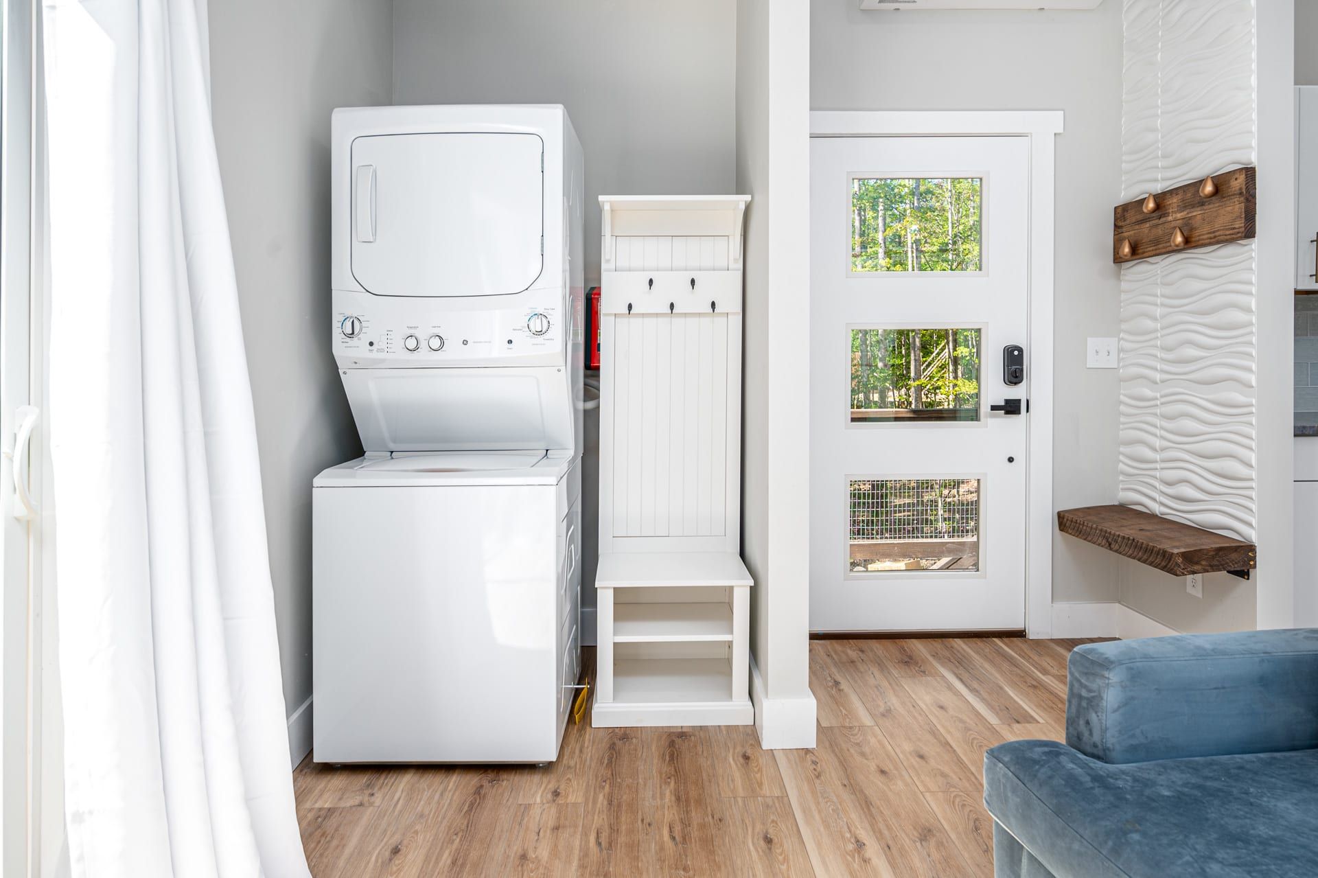 Une petite buanderie comprenant un lave-linge et un sèche-linge, un meuble blanc et une porte avec des fenêtres.