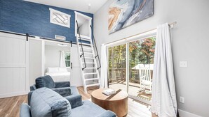 A modern living room with a blue sofa, a wooden coffee table, and a staircase leading to a balcony.